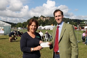In sight of Dunster Castle, Patrick Rose presents RABI's Pam Wills with a cheque for the sum raised by the GWCT's Somerset committee